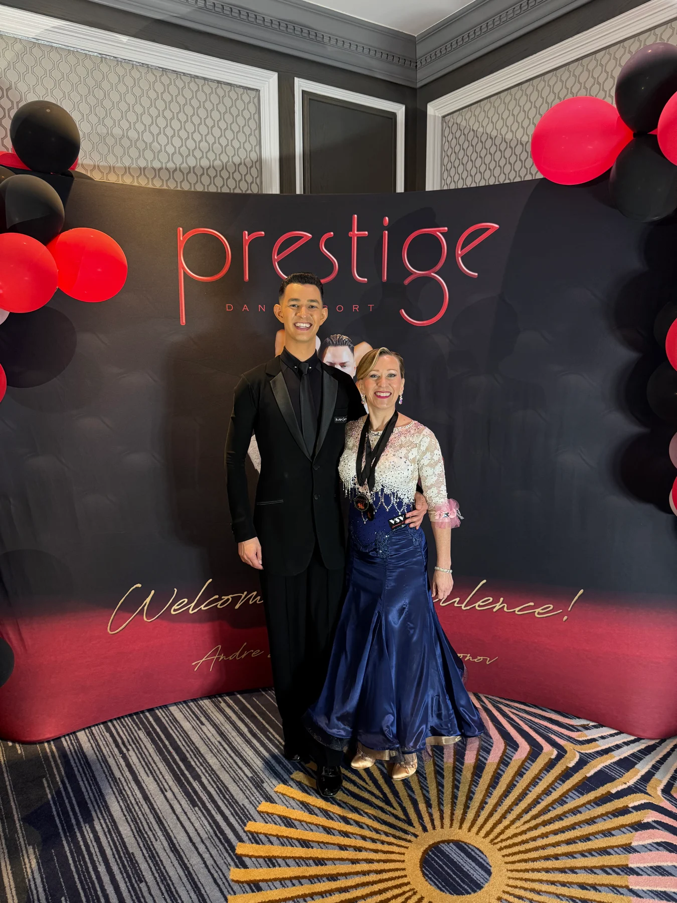 Alexander and a student in a white and blue dress at Prestige