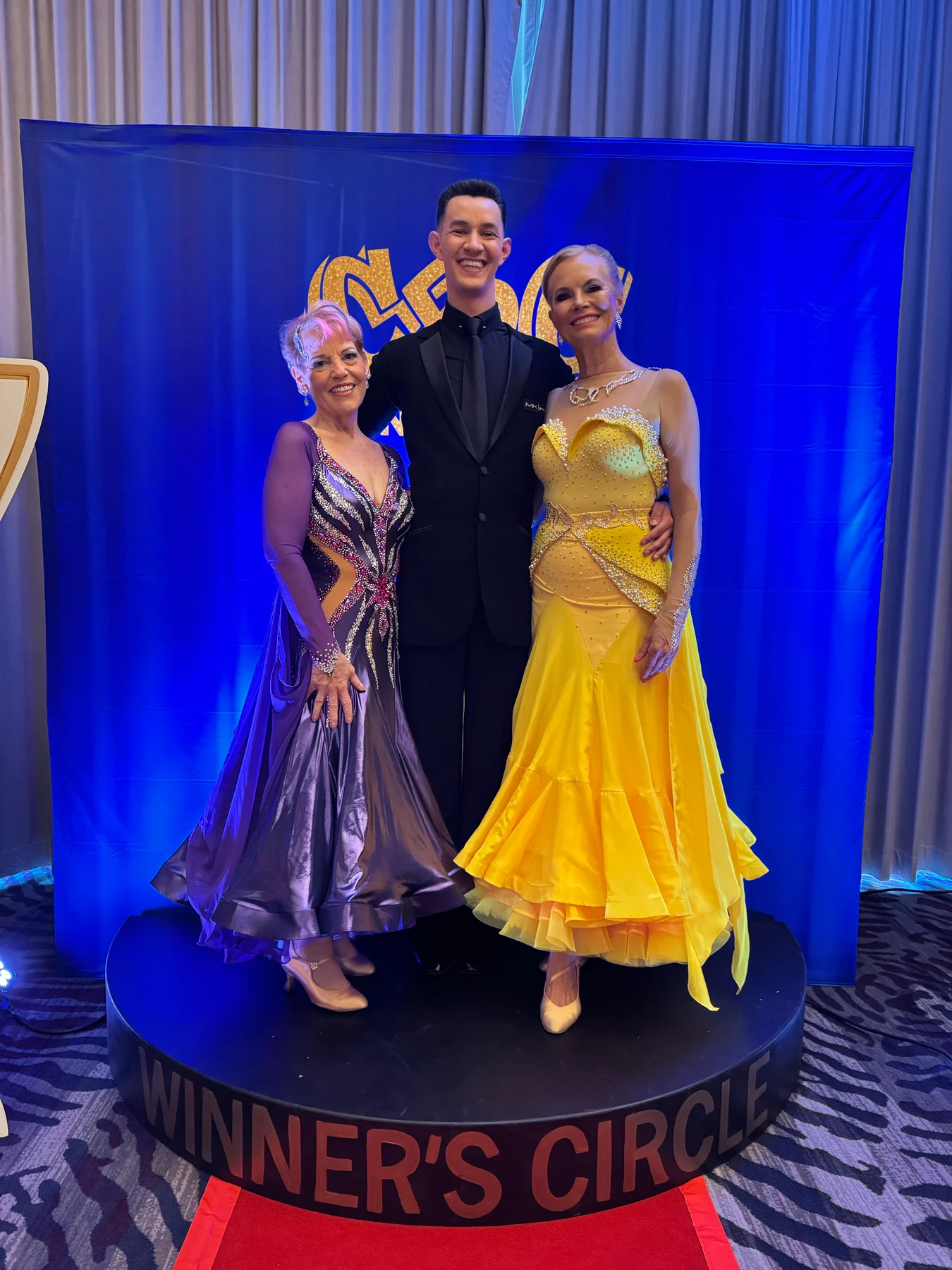 Alexander with two students celebrating at a dance competition