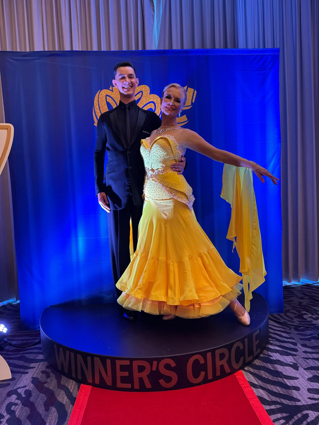 Alexander posing with a student in a yellow gown at a competition
